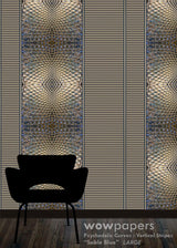 A large-scale wallpaper sample featuring vertical stripes with psychedelic, wavy geometric patterns in metallic gold, silver, and blue, shown with a black chair silhouette in the foreground on a wood floor. Text at the bottom reads 'wowpapers Psychedelic Curves Vertical Stripes "Sable Blue" LARGE'.