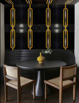 Dining area with a round table, chairs, and decorative elements against a black and yellow wallpaper