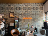 Cozy cafe interior with patterned wall, 'Ciao Bella Coffee' sign, and patrons using laptops.