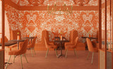 Dining area with orange chairs and patterned walls in a restaurant setting