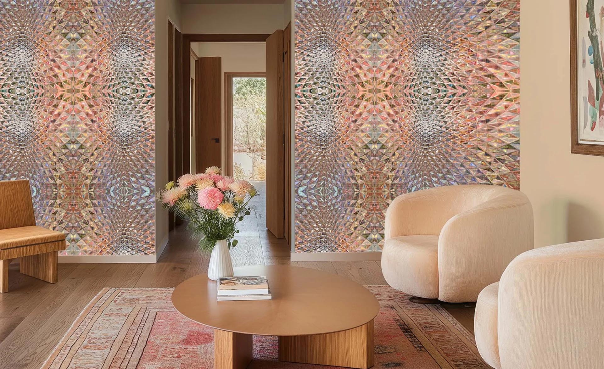 A modern living room featuring two walls covered in a detailed, multicolored geometric mosaic patterned wallpaper. The room is furnished with a round wooden coffee table, a beige modern armchair, a wooden bench, and a patterned rug.