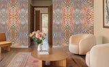 A modern living room featuring two walls covered in a detailed, multicolored geometric mosaic patterned wallpaper. The room is furnished with a round wooden coffee table, a beige modern armchair, a wooden bench, and a patterned rug.