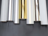Rolls of metallic paper in silver, gold, and other colors on a gray background
