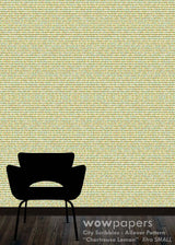 A textured wallpaper sample with a repeating micro-pattern in pale yellow, beige, and muted green, shown on a wall behind a black chair silhouette. Text at the bottom reads 'wowpapers City Scribbles : Allover Pattern "Chartreuse Lemon" Xtra SMALL'.